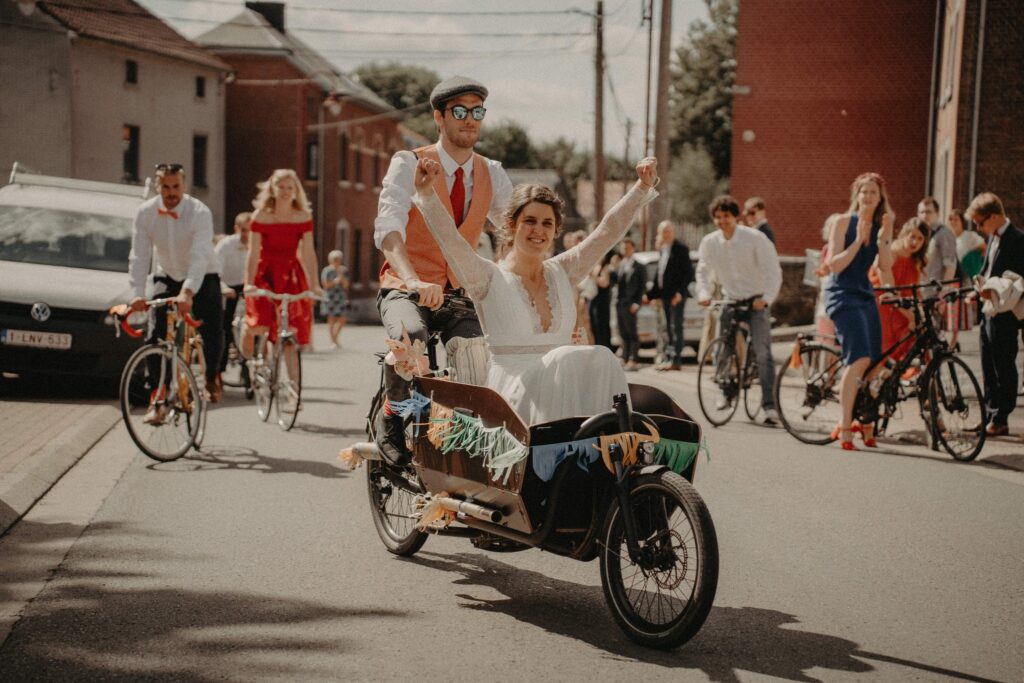 Couple de mariés à vélo avec leurs proches