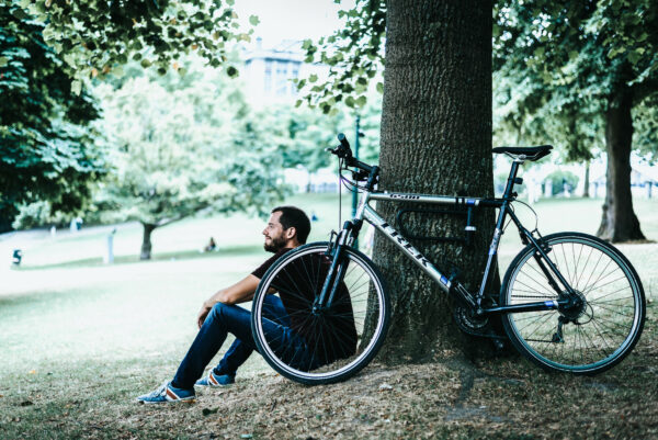Un homme assis au pied d'un arbre avec son vélo à côté de lui